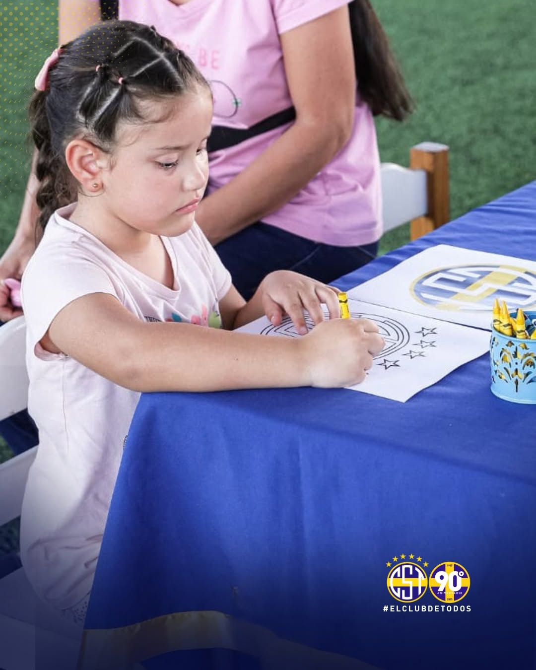 Una niña coloreando el escudo del club